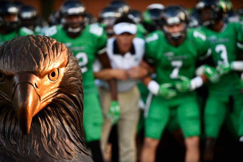 North Texas interim head coach Mike Canales locks arms with his players before they take the...