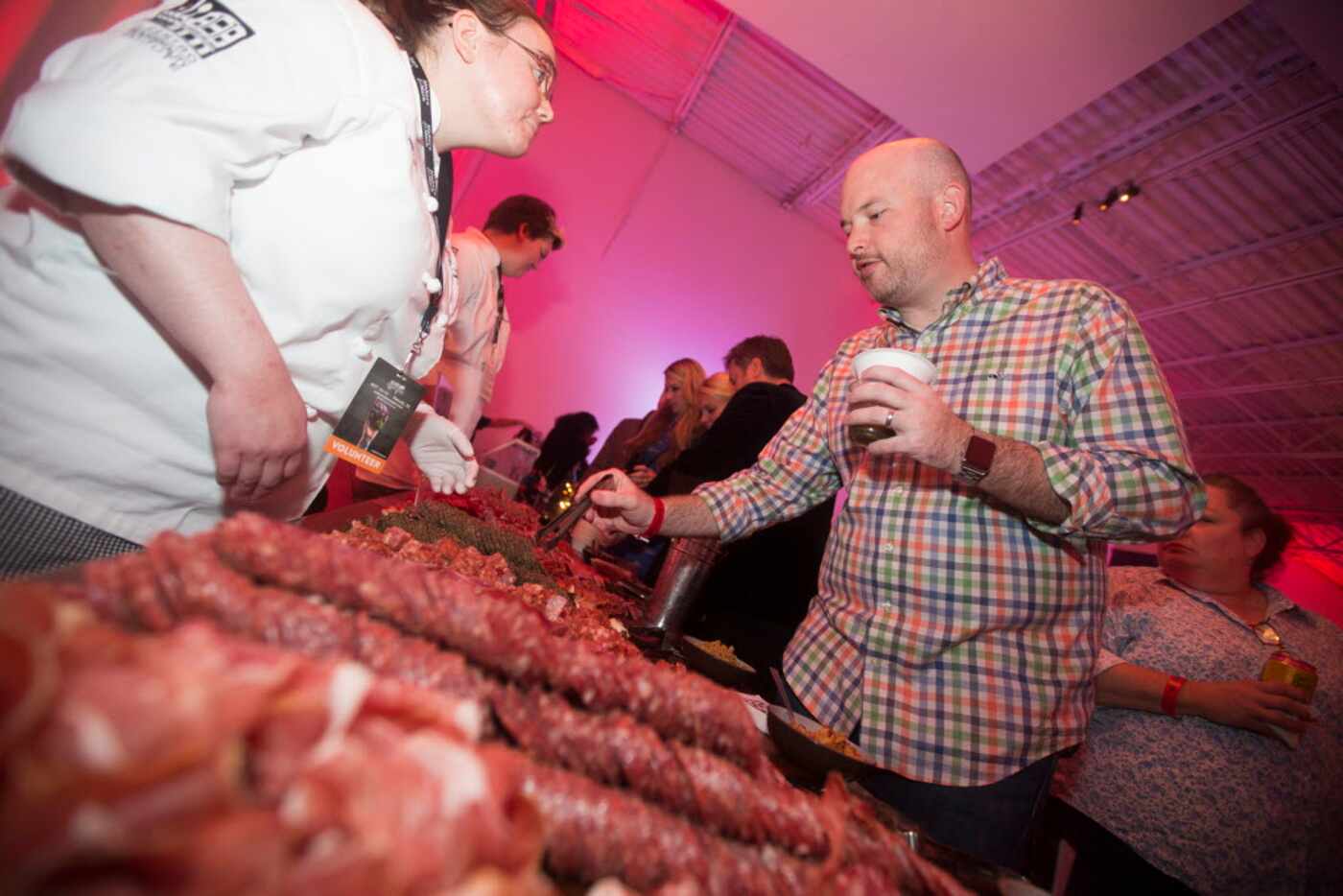Justin Pate selects samples from a large table of meats during the Chefs for Farmers Butcher...