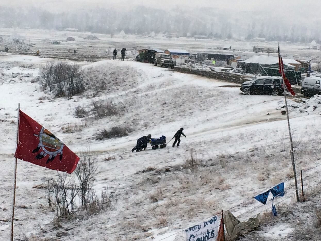 People push belongings up a hill at the Dakota Access pipeline opponents' main protest camp...