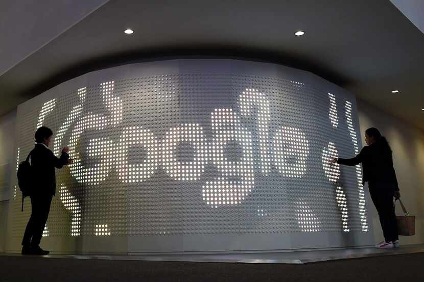 Two people visit the stand of Google on the second day of the Mobile World Congress on...