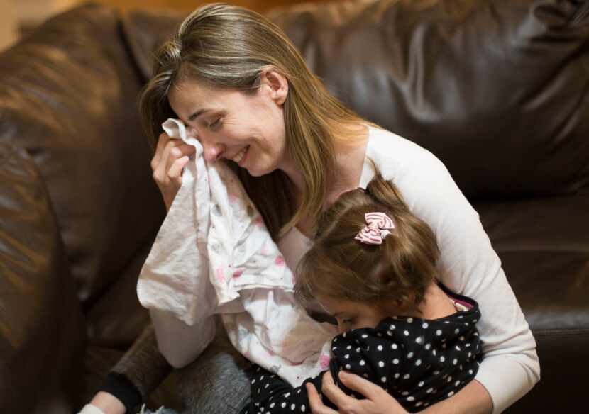Katiele Fischer, overcome with emotion, cradles her daughter Anny, who has the rare genetic...