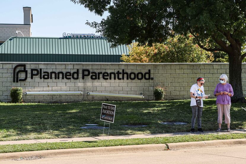 Protesters stood on the sidewalk near Planned Parenthood next to anti-abortion signs in...