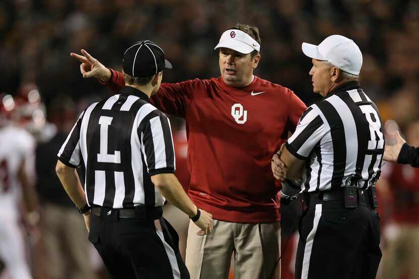 Oklahoma coach Bob Stoops argues with line judge Walt Coleman and referee Mike Defee during...