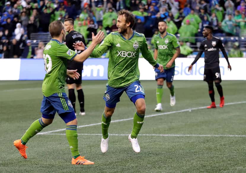 Seattle Sounders midfielder Magnus Eikrem, second from left, is greeted by forward Harry...