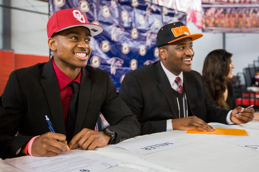 Bishop Dunne Catholic School wide receiver Adrian Miller, left, signs a letter of intent to...