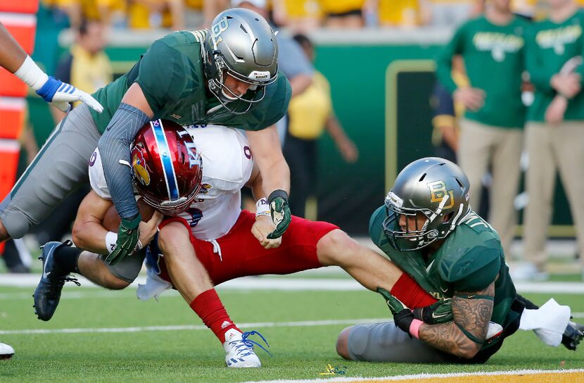 Kansas quarterback Carter Stanley (9) is tackled by Baylor linebackers Jordan Williams (38)...