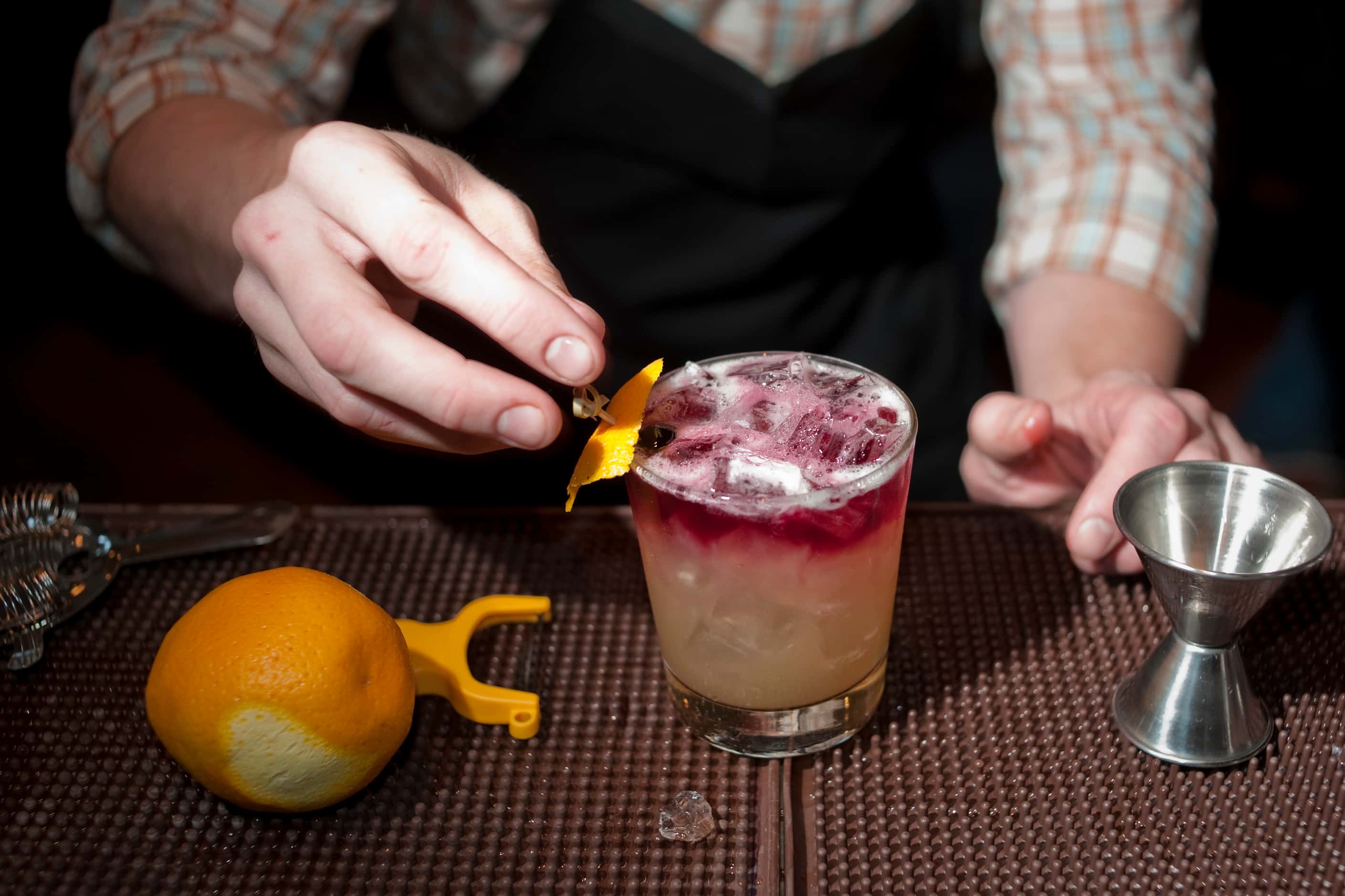 Bartender Eddie Eakin puts a lemon garnish on an Eight Street Sour cocktail during...
