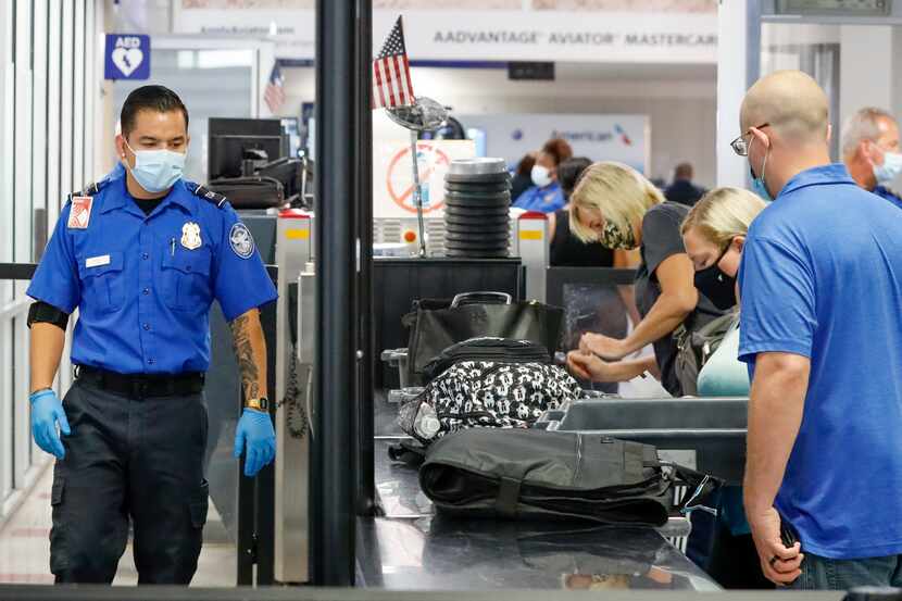 A Transportation Security Administration agent watches travelers place their belongings in...