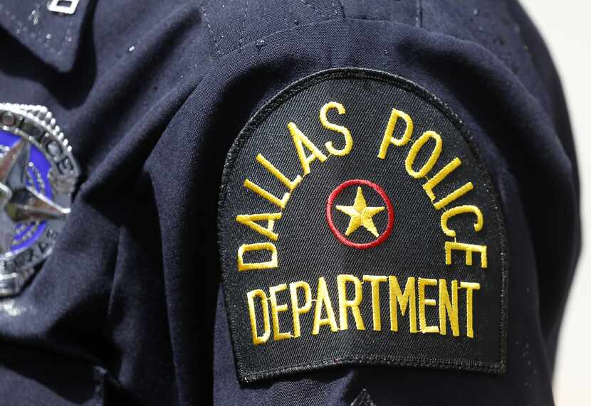 A police officer stands outside Dallas Police headquarters after a gunman opened fire...