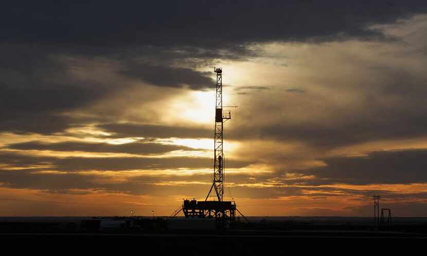 This 2014 file photo shows a drilling rig in Howard County, Texas as the sun sets. 