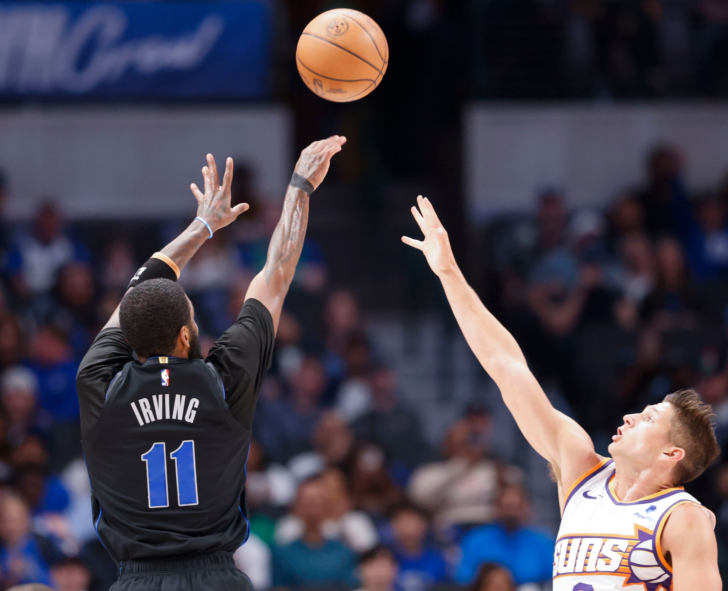 Dallas Mavericks guard Kyrie Irving (left) shoots a three-pointer over Phoenix Suns guard...