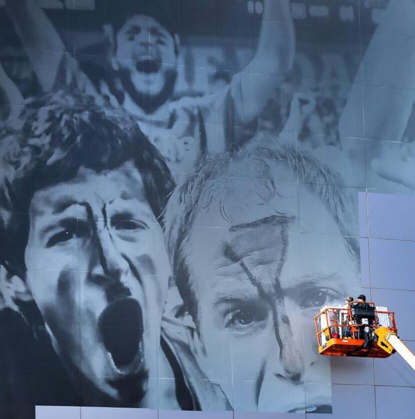 
Workers spent part of Wednesday putting a March Madness mural on AT&T Stadium, where the...
