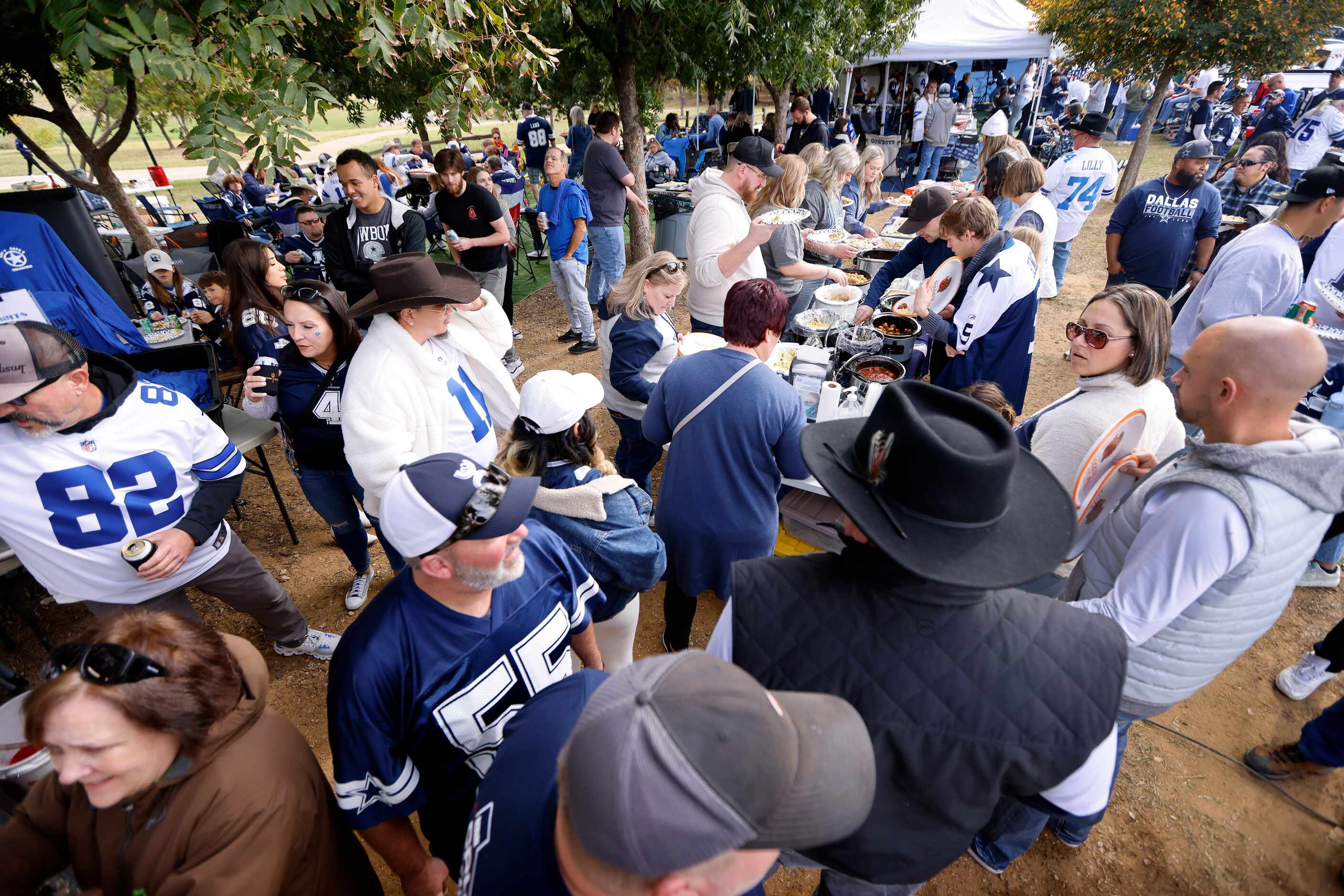 Dallas Cowboys fans at Lot 4 Gate 6’s tailgate party get in line for Thanksgiving Day dinner...