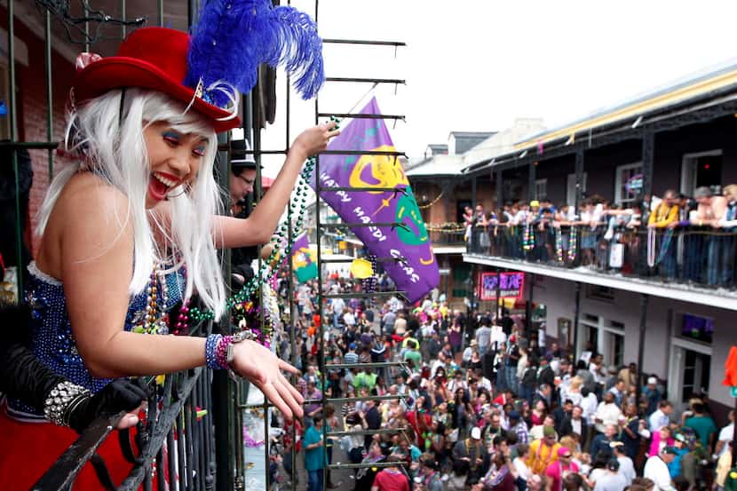 Malia Miyashiro, of California, throws beads from a Bourbon St. balcony to Mardi Gras...