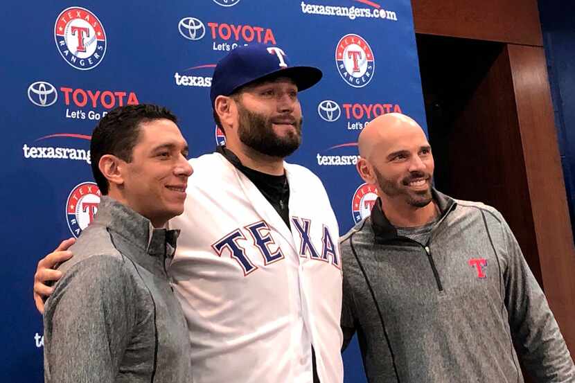 Newly signed Texas Rangers pitcher, Lance Lynn, center, wears his new team jersey as he...