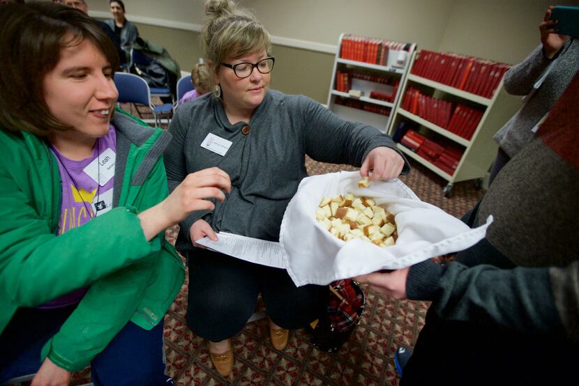 Jacob Smith (right) offers bread to Leah Battalora (left) and Kathryn Williams during...