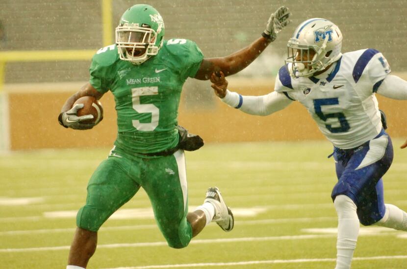 University of North Texas senior  running back Lance Dunbar (5) fends off a tackle by Middle...
