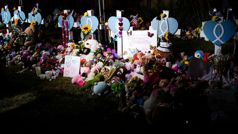 Flowers, toys and messages surround a row of eight crosses as memorial to mass shooting...