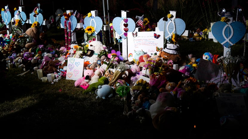 Flowers, toys and messages surround a row of eight crosses as memorial to mass shooting...