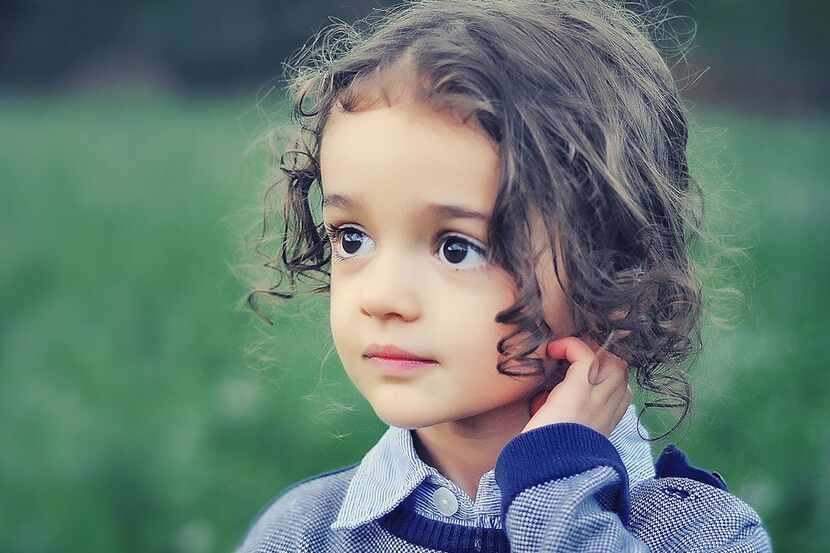 dark-haired little girl with big brown eyes and a blue sweater