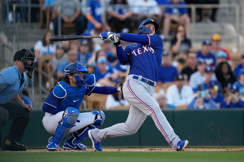 Texas Rangers' Corey Seager follows through on a swing during the first inning of a spring...