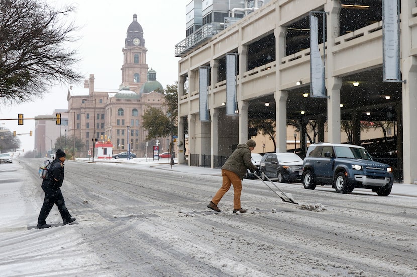 Derek Sutter, building manager for Tarrant County, shovels sleet and ice from a sidewalk on...