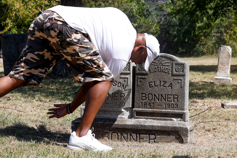 Antonia Suber brushes aside freshly mowed grass from the double headstone of Black landowner...