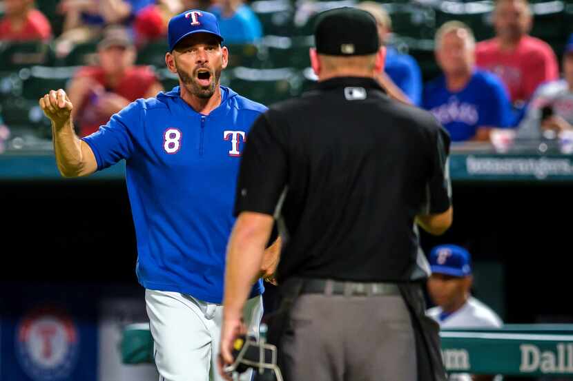 El manager de los Texas Rangers, Chris Woodward, protesta un decisión del umpire Mike...
