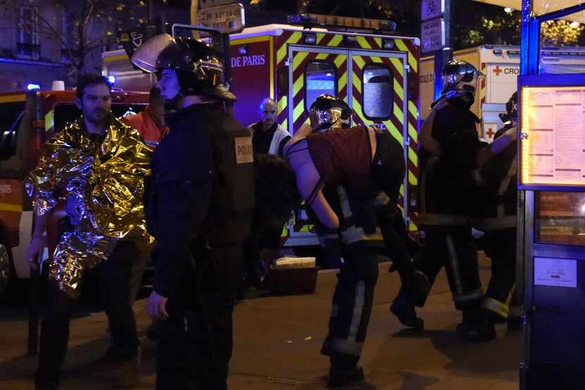 Rescuers vacuate a woman near the Bataclan concert hall in central Paris.