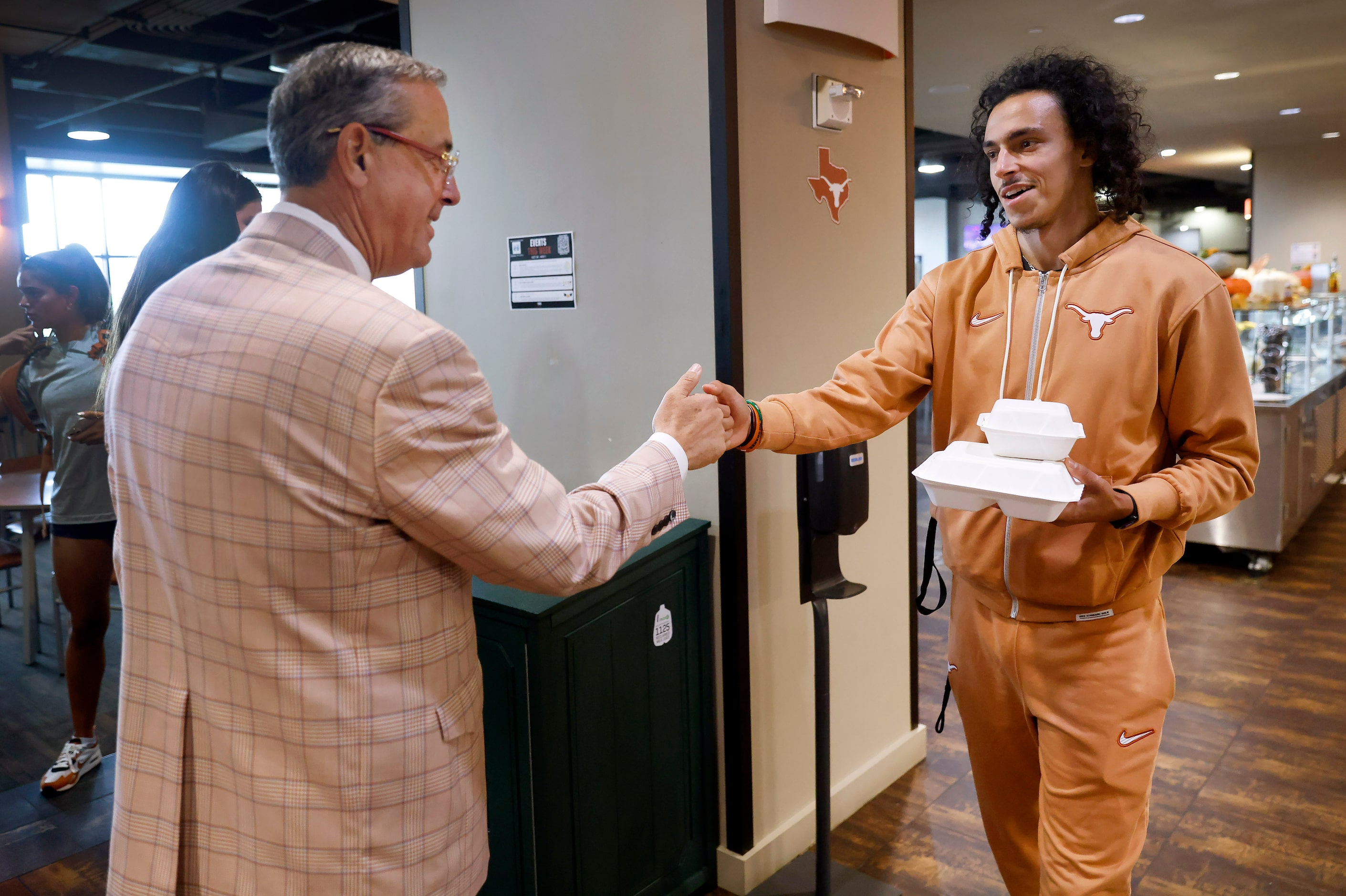 University of Texas Athletic Director Chris Del Conte (left) gives a fist bump to track...