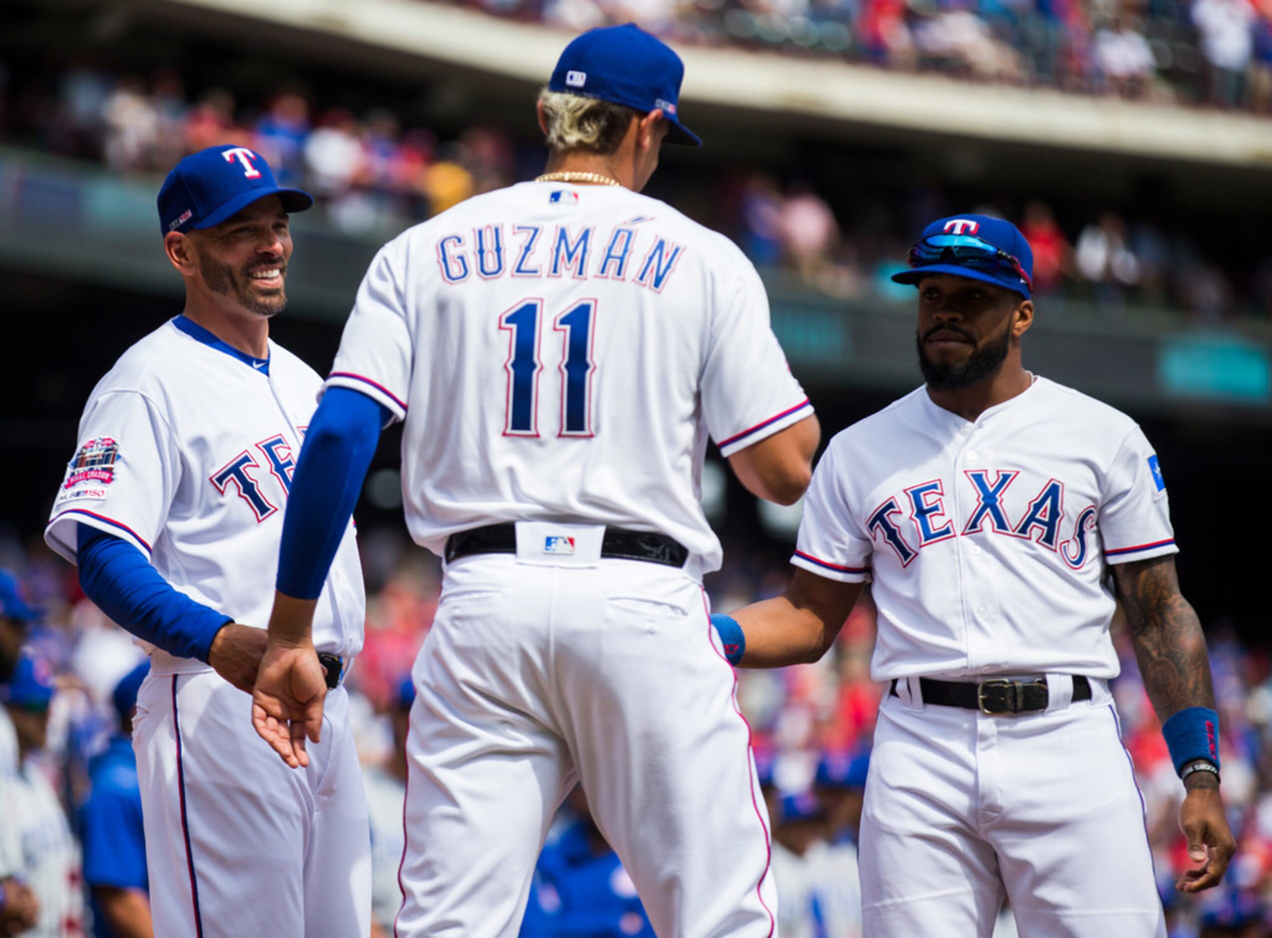 Texas Rangers manager Chris Woodward (8) and center fielder Delino DeShields (3) greet first...