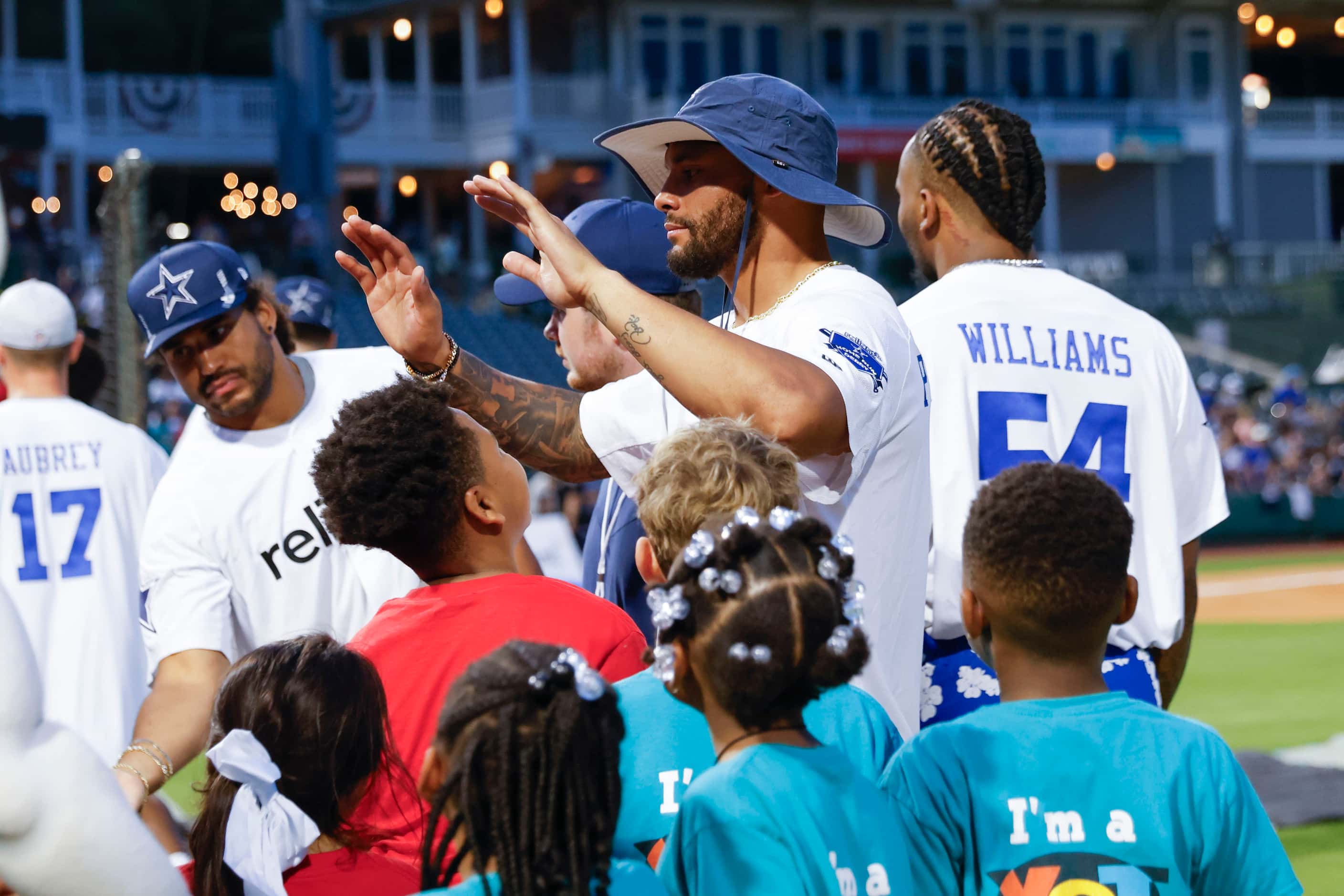 Dallas Cowboys quarterback Dao Prescott (center) high-fives young fans as the players exit...