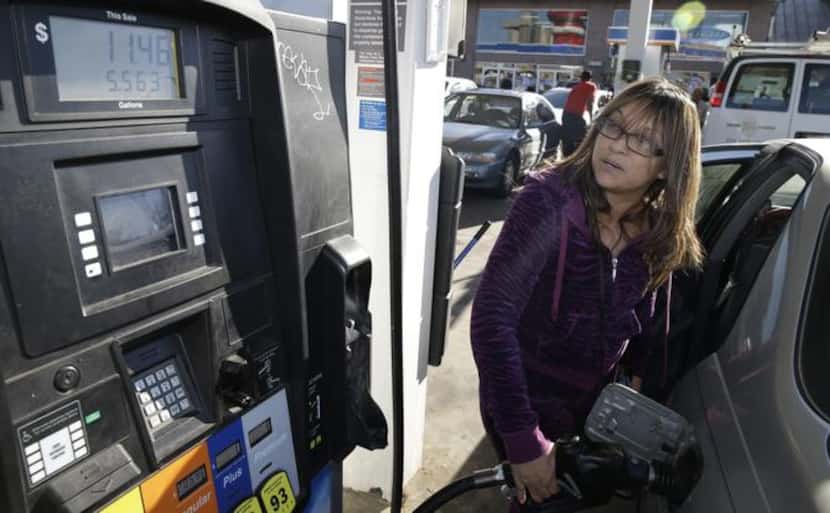 
Alva Ibarra gases up at the Fuel City gas station in Dallas. The plunge in the price of oil...
