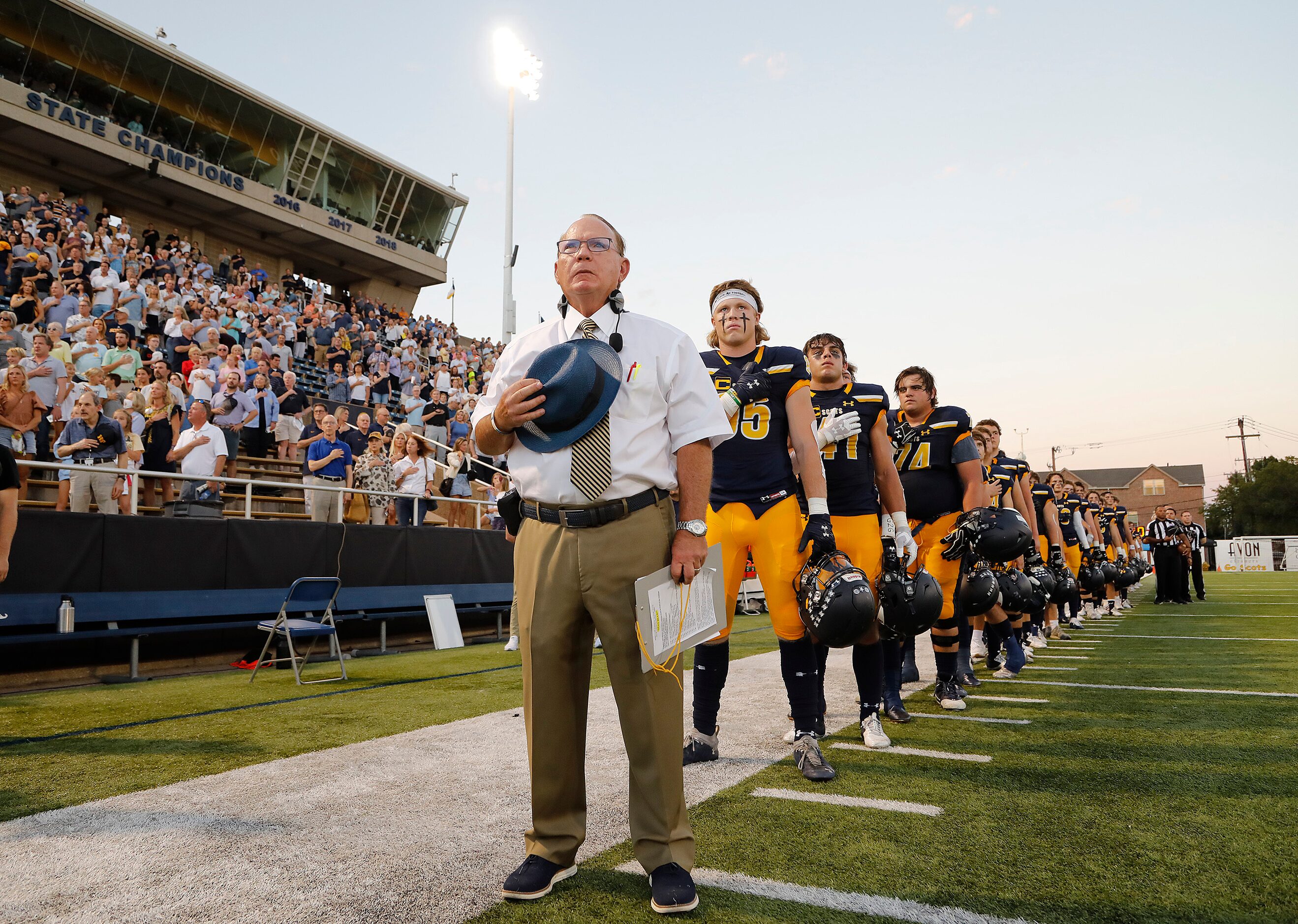 Highland Park High School head coach Randy Allen stands at attention with his team for the...