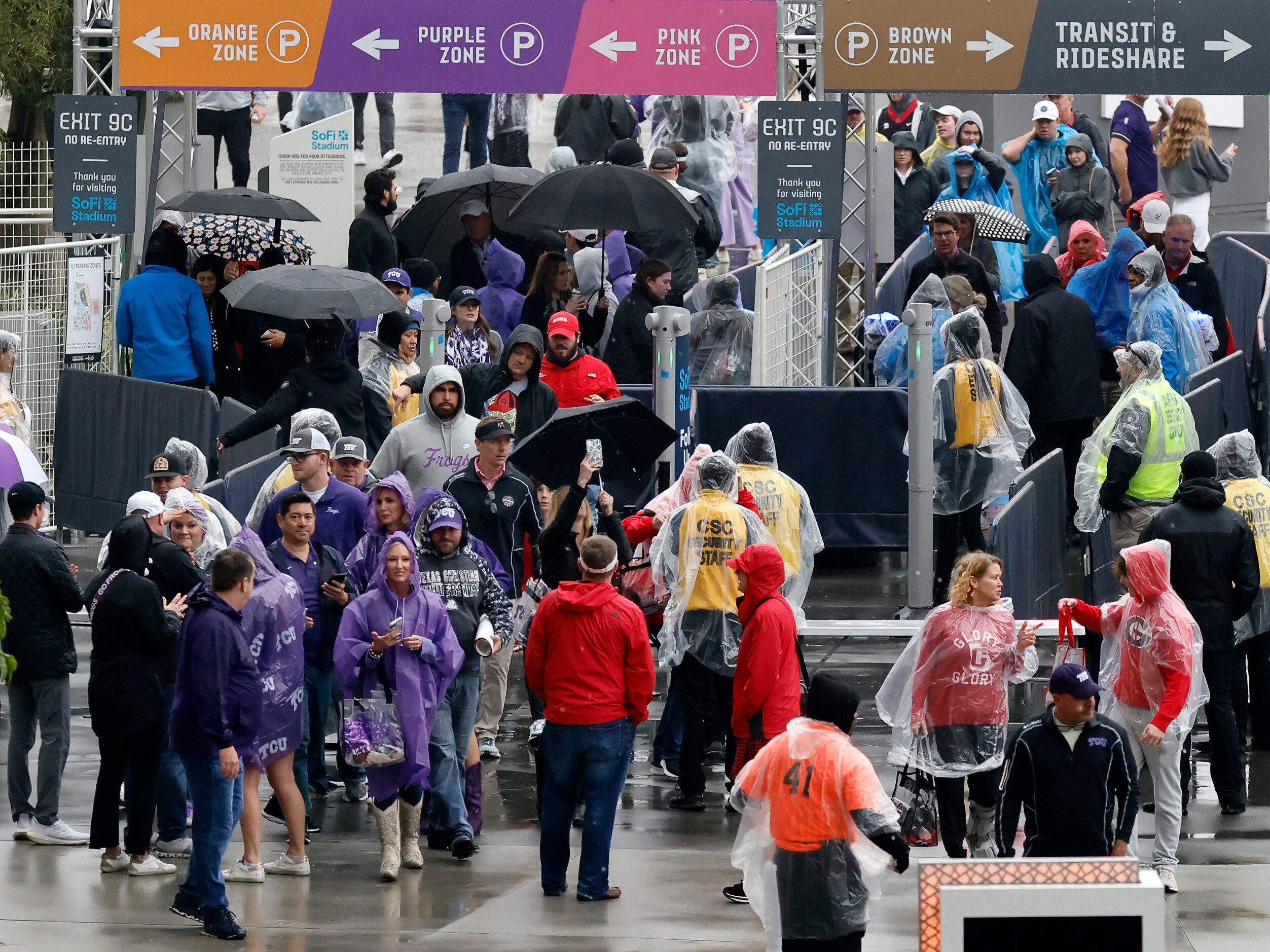 TCU Horned Frogs and Georgia Bulldogs fans make their way through the rain for the CFP...