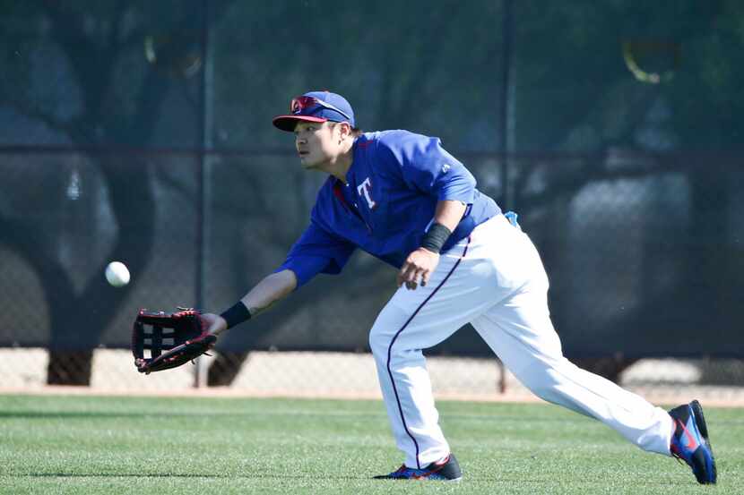 Texas Rangers left fielder Shin-Soo Choo reaches down to make a catch during fielding drills...