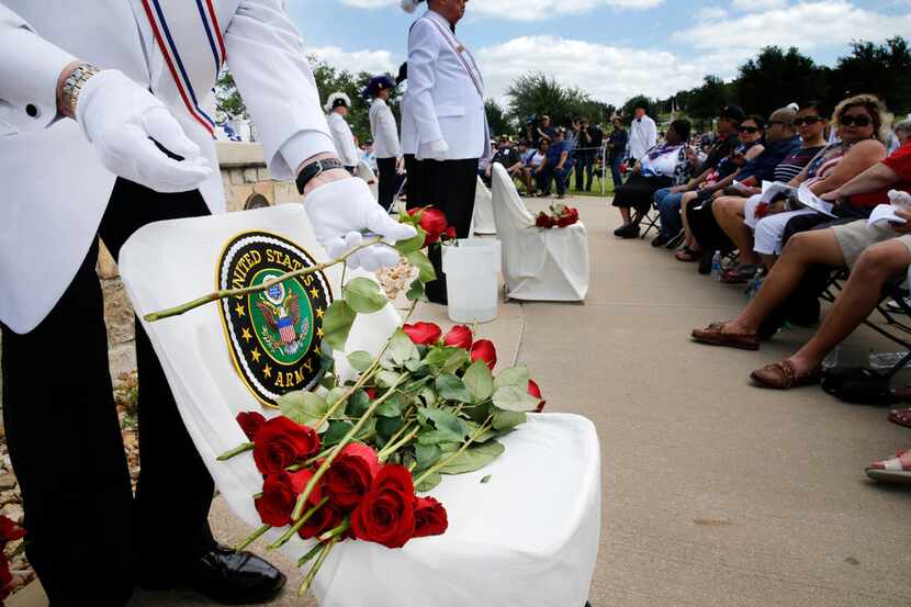Jim Sammons of the Knights of Columbus places roses on an empty chair designated for the...