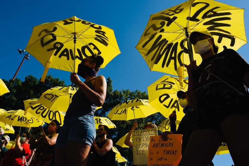 Protestors hold yellow umbrellas with names of people who were killed by police during a...