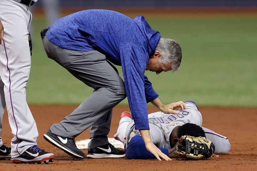 Texas Rangers trainer Kevin Harmon helps shortstop Jurickson Profar after he was injured in...