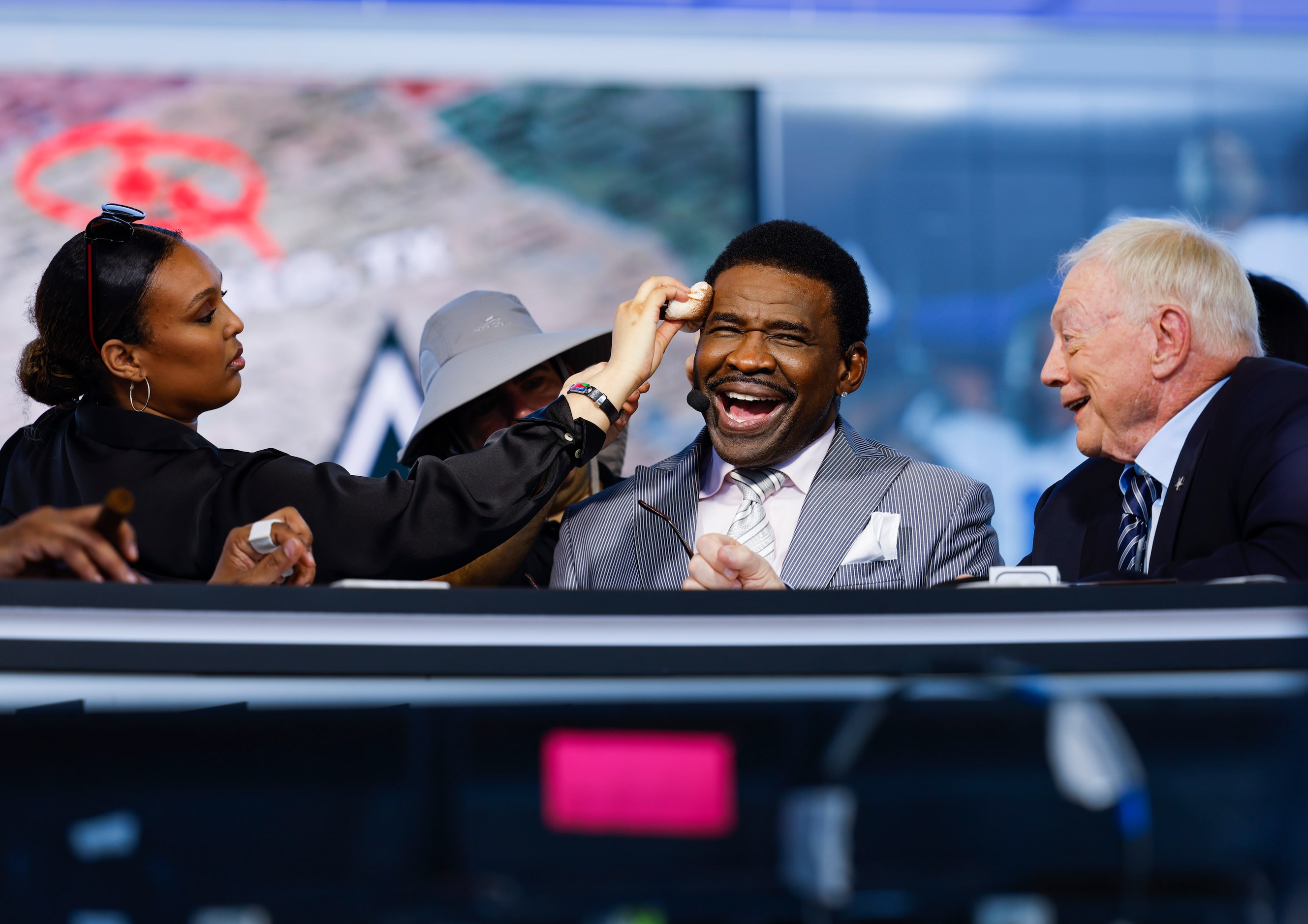 A crew member grooms former Dallas Cowboys player Michael Irvin, middle, as Cowboys owner...