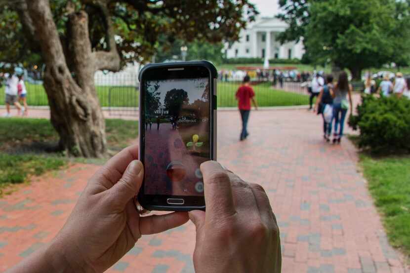 A woman holds up her cellphone as she plays the Pokemon Go game in front of the White House. 