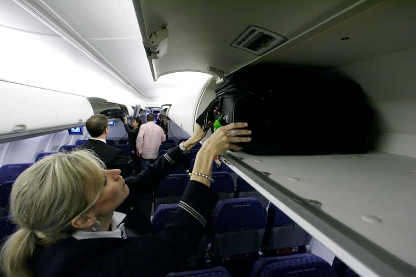 American Airlines flight attendant Renee Schexnaildre demonstrated the overhead baggage area...