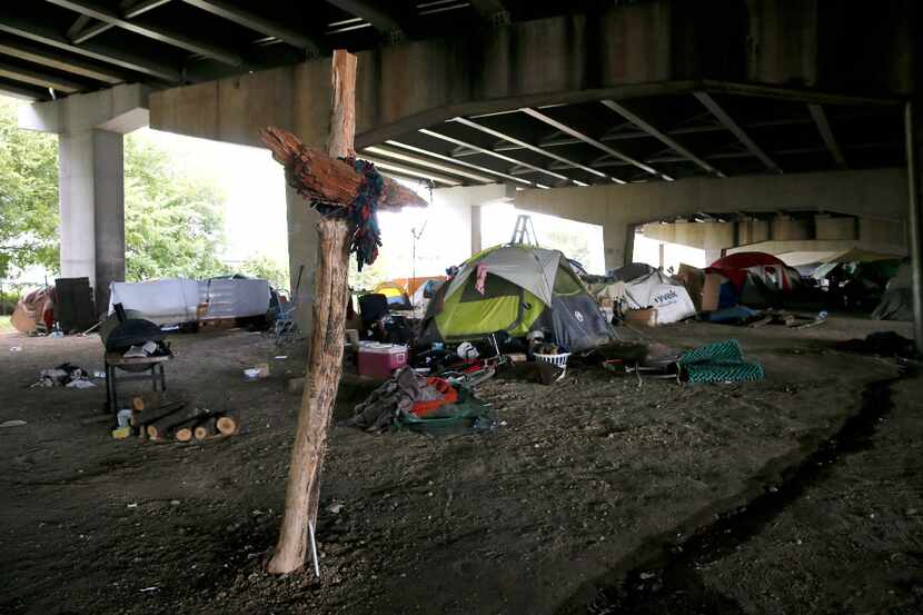 In the shadow of a makeshift cross, homeless residents live in an encampment beneath...