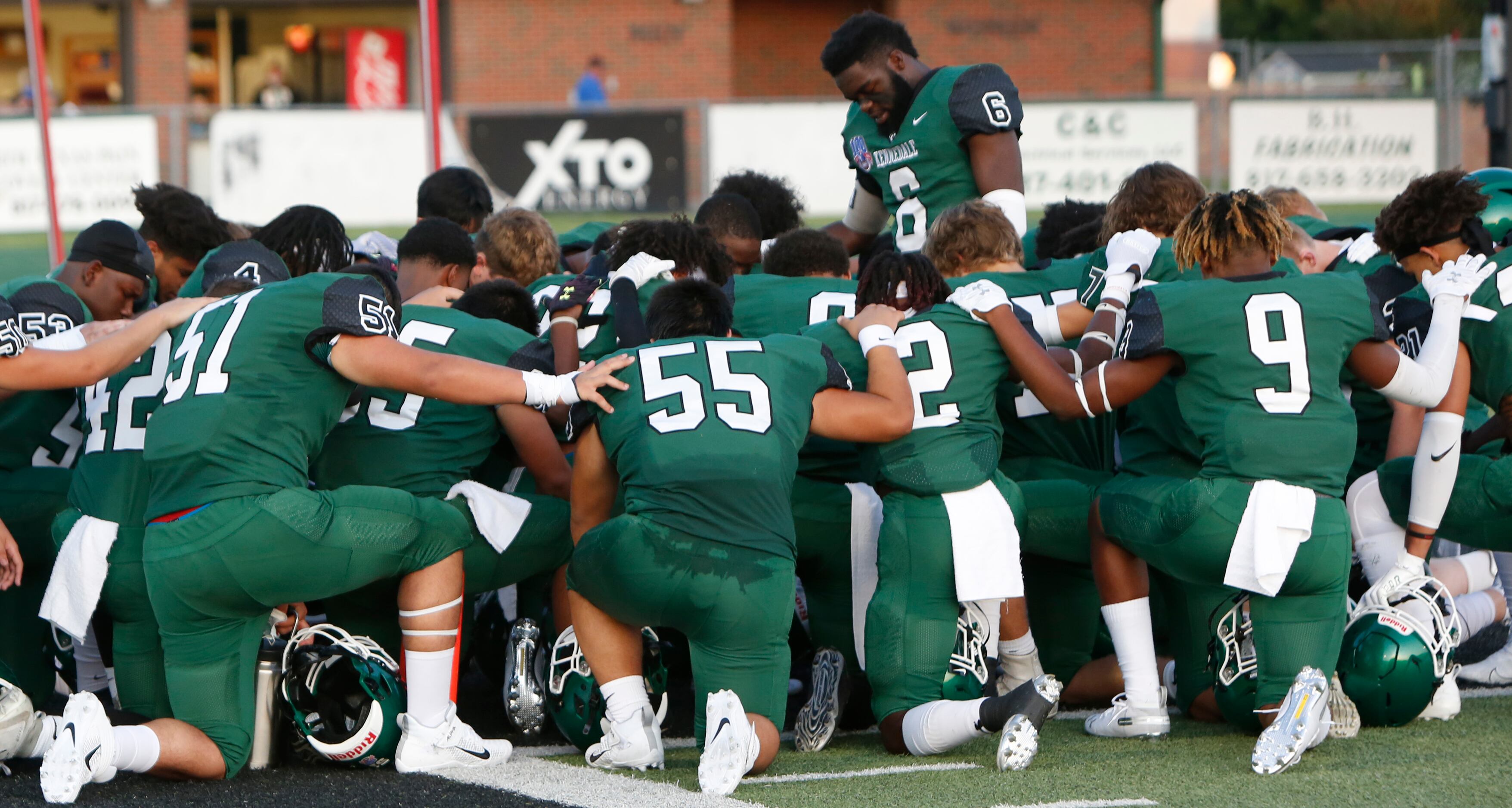 Members of the Kennedale Wildcats pause to pray in the end zone before the opening kickoff...