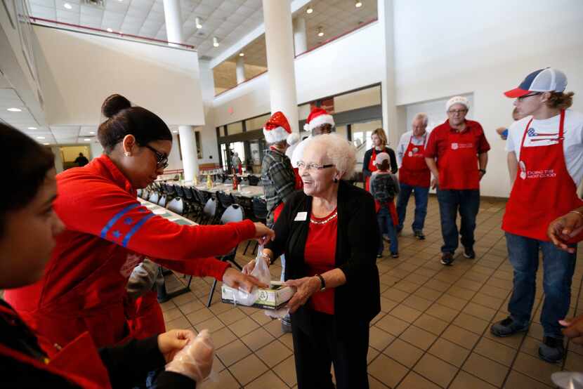 Nancy Kerley, 73, hands out gloves to Diana Arce (left) before the Christmas meal served by...