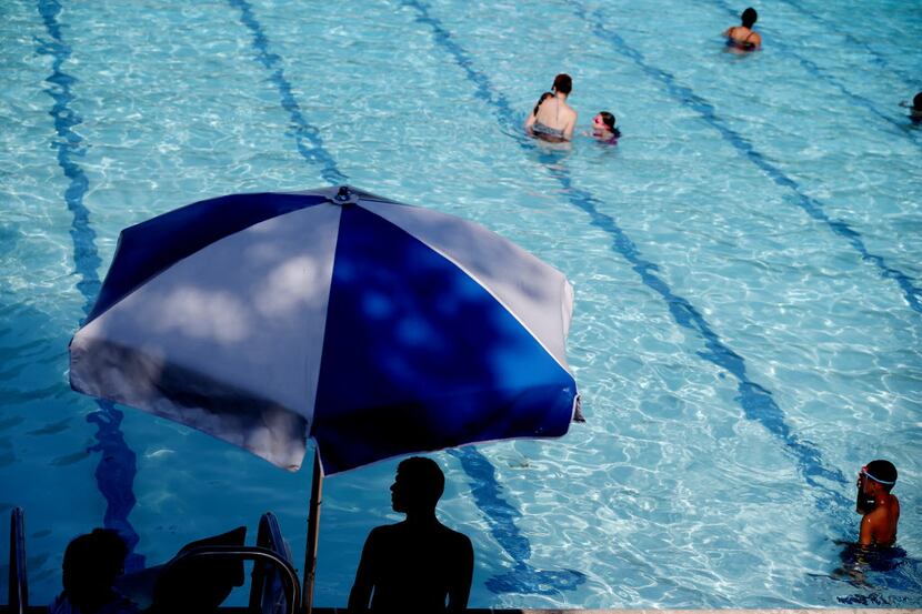 Individuals swim at the Lake Highlands North Recreation Center swimming pool in Dallas June...