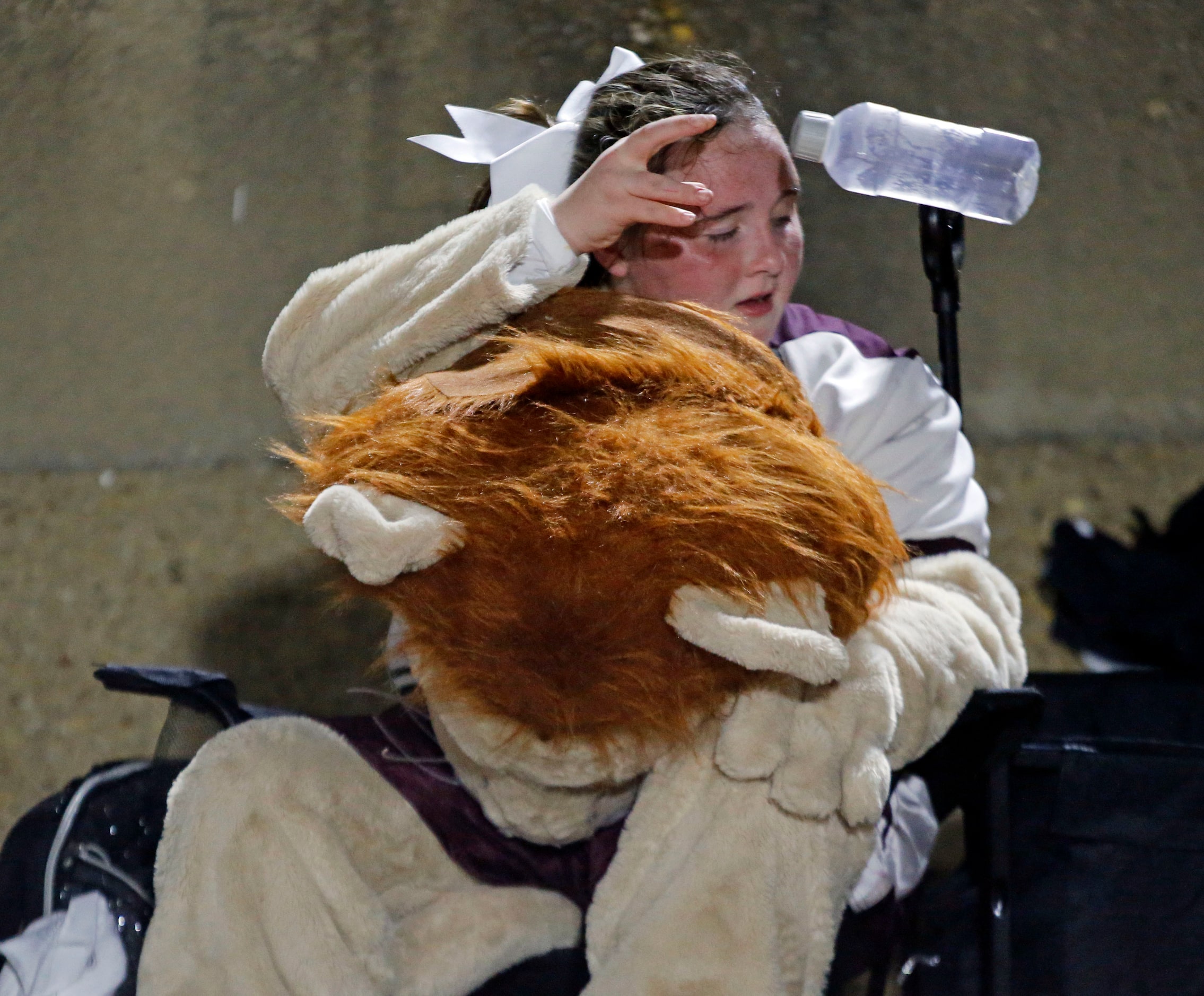 The Ennis high Lion mascot tosses her used water bottle during a break during the first half...