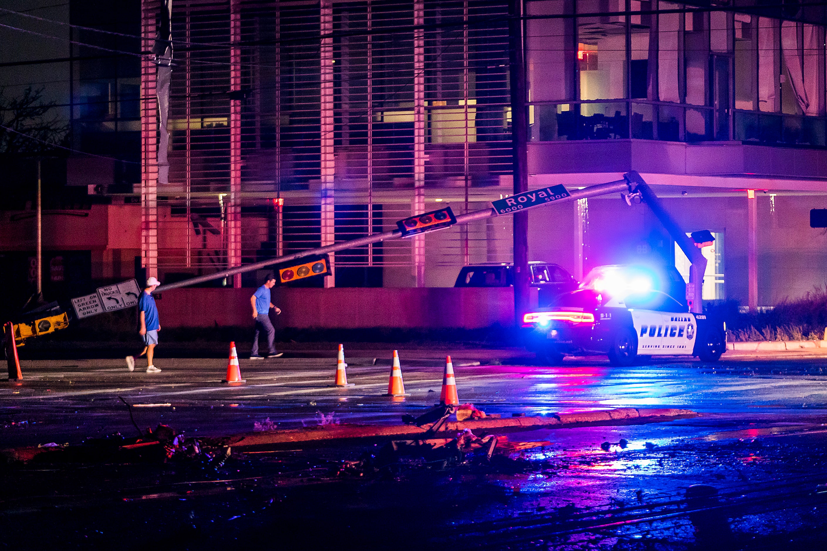 People walk past the downed stoplight at the intersection of Royal and Preston from storm...