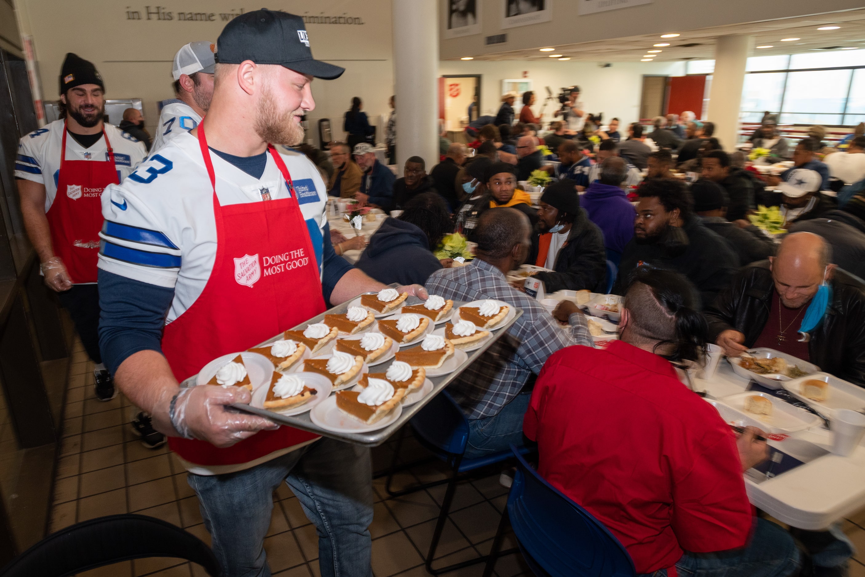 Dallas Cowboys starting center Tyler Biadasz carries a tray of pumpkin pies while serving...