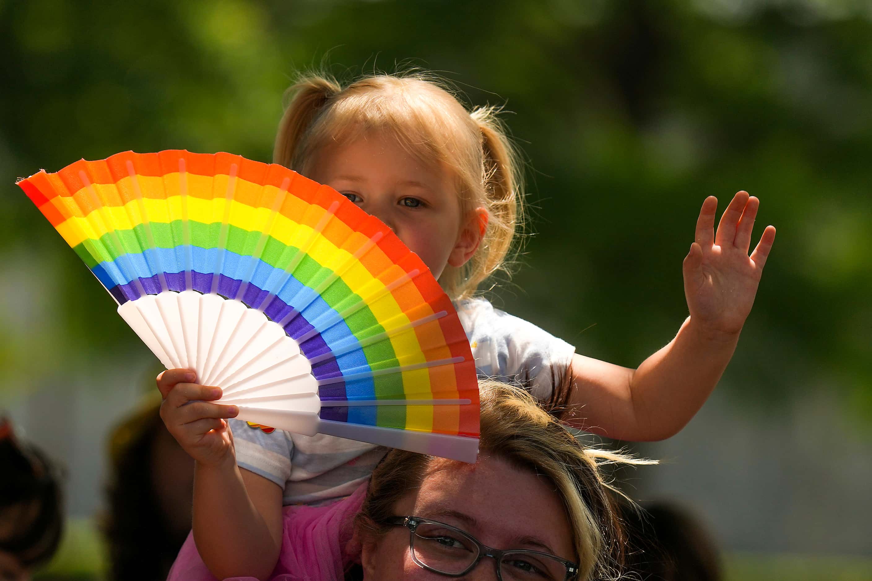 A spectator waves a rainbow fan during the annual Alan Ross Texas Freedom Parade celebrating...